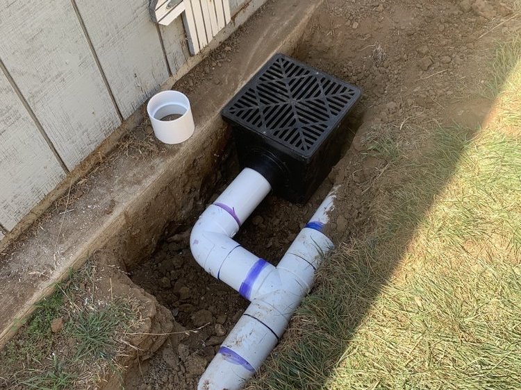 Catch basin and PVC fittings set in a trench before backfill
