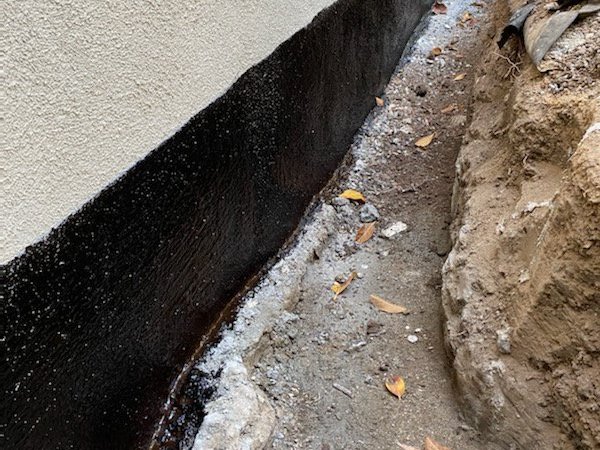 Waterproof coating on a foundation wall with gravel placed at the base