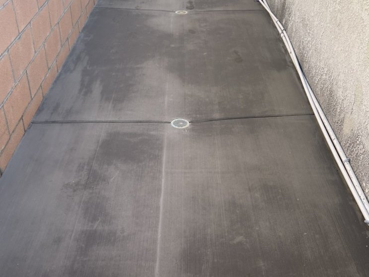 Newly poured concrete side-yard slab with a drain set flush in the surface
