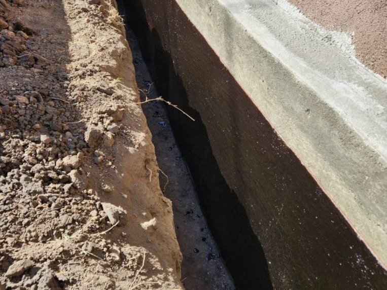 Waterproofing membrane on a below-grade wall with the trench open alongside