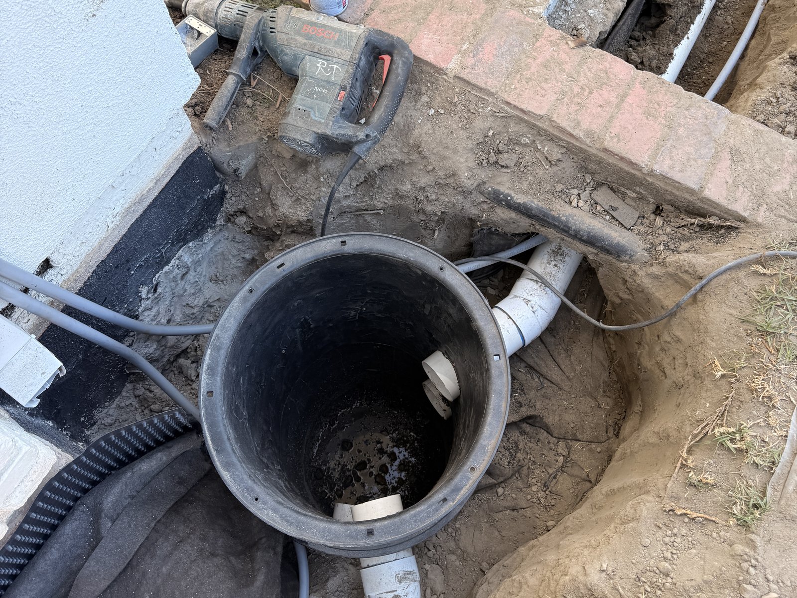 Drainage basin set into the ground with drain lines connected