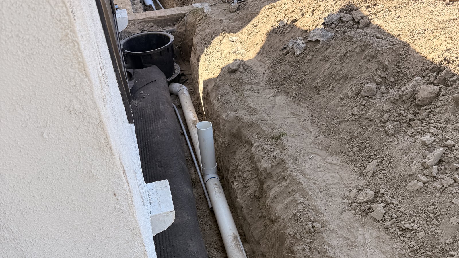 Open trench with drain pipe running along a home's foundation