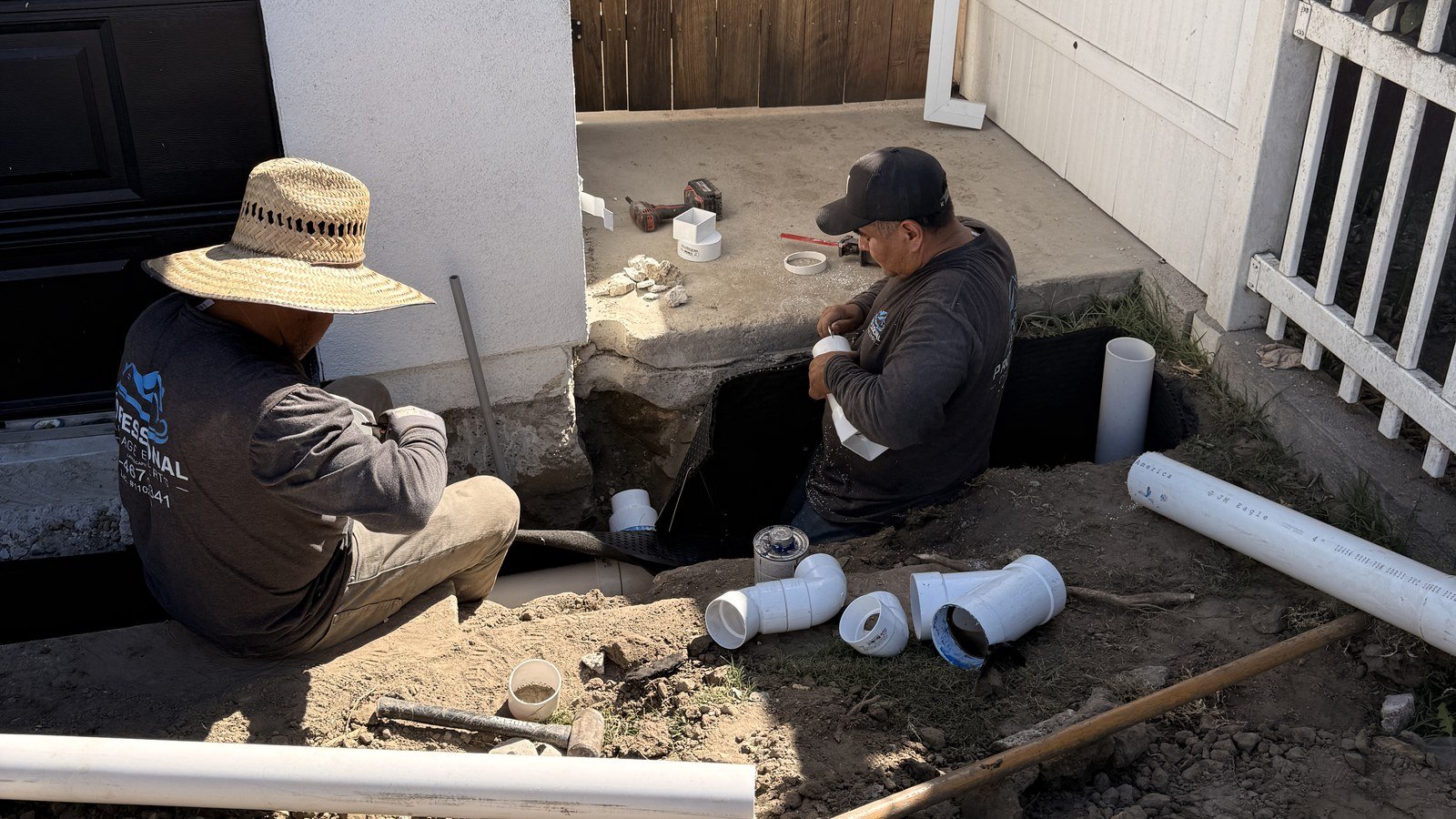 Professional Drainage Experts crew members assembling PVC drain line at a home