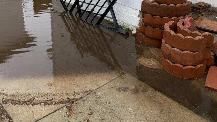 Standing water pooling against a home after rain, a common sign of a drainage problem