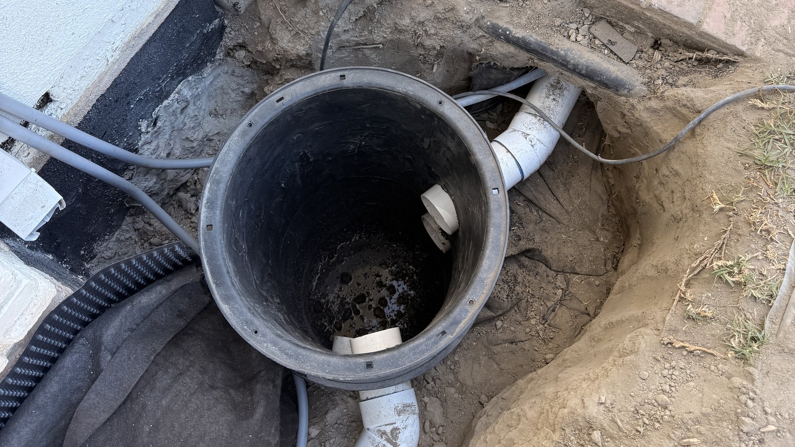 Drainage basin set into the ground with drain lines connected